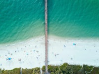 an aerial view of a beach with people and a pier