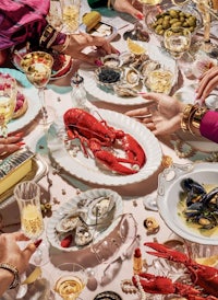 a group of people sitting around a table with lobsters and wine