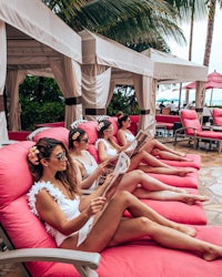 a group of women sitting on pink lounge chairs