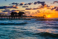 a pier with waves crashing over it at sunset