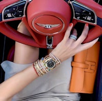 a woman sitting in a red car with a watch on her wrist